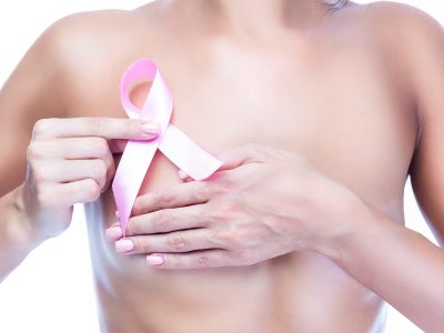 Caucasian Topless Woman With Folded Hands Holding Pink Solidarity Ribbon As Breast Cancer Awareness Symbol and Women Healthcare Concept of Campaign Against Cancer. Vertical Shot